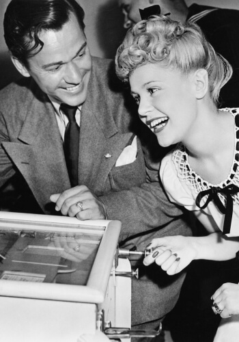 Old photo of a couple playing pinball machine